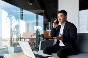 Thinking asian businessman businessman, talking on the phone working in a modern office, listening seriously